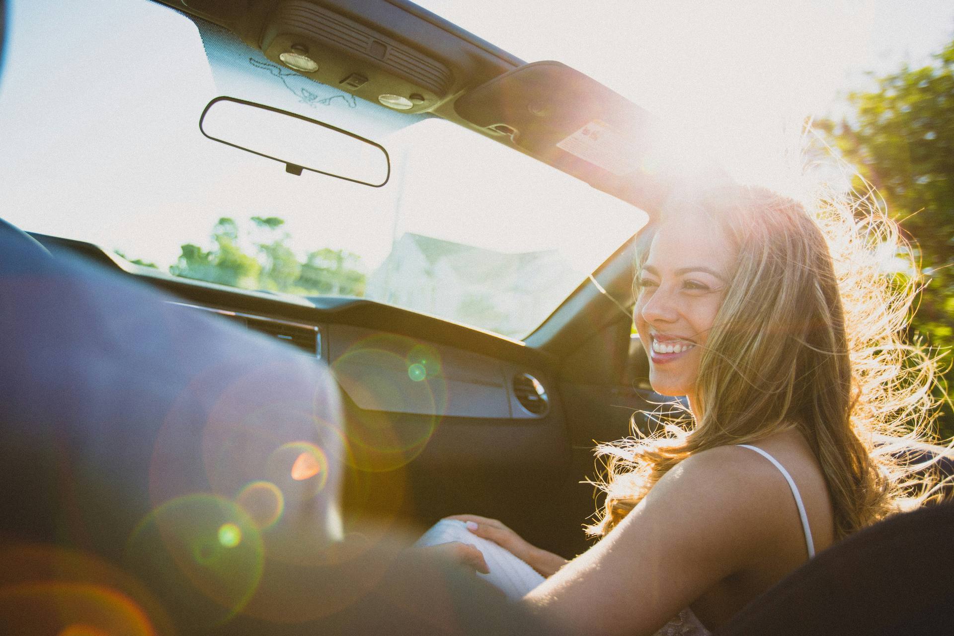 A traveller smiling in the passenger seat of a car in the golden evening light